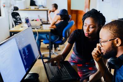 a woman showing something on laptop screen to a man in a business setting.